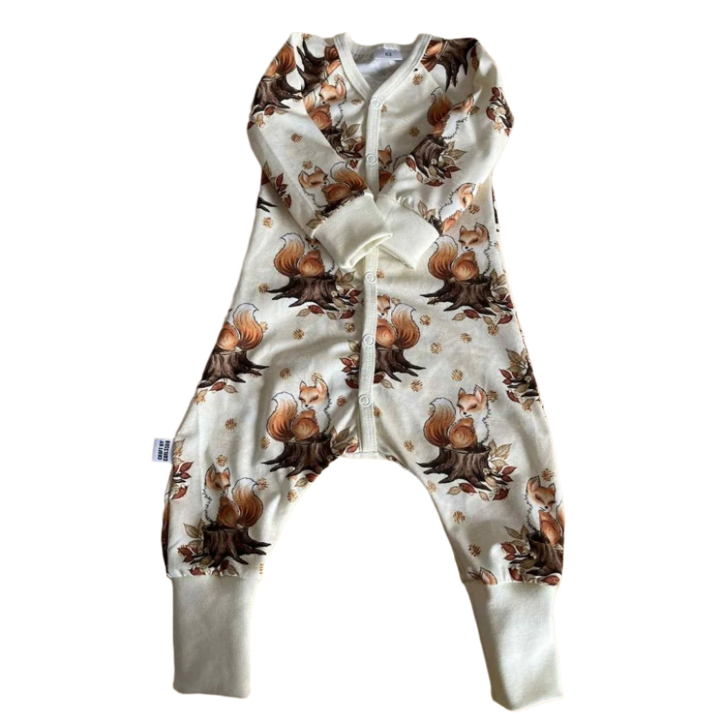 Babypyjamas med tryckknappar och långa ärmar och ben. Vit botten med mönster av söta bruna rävar.