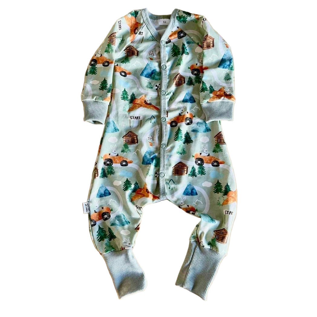Vit långärmad pyjamas med mönster av orangea morotsliknande racerbilar och flygplan som körs av kaniner. 
