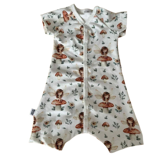 Vit pyjamas i ekologiskt tyg, korta ärmar och ben, tryckknappar hela vägen. Gullligt mönster med en trollsländeflicka på svamp i skogen. 