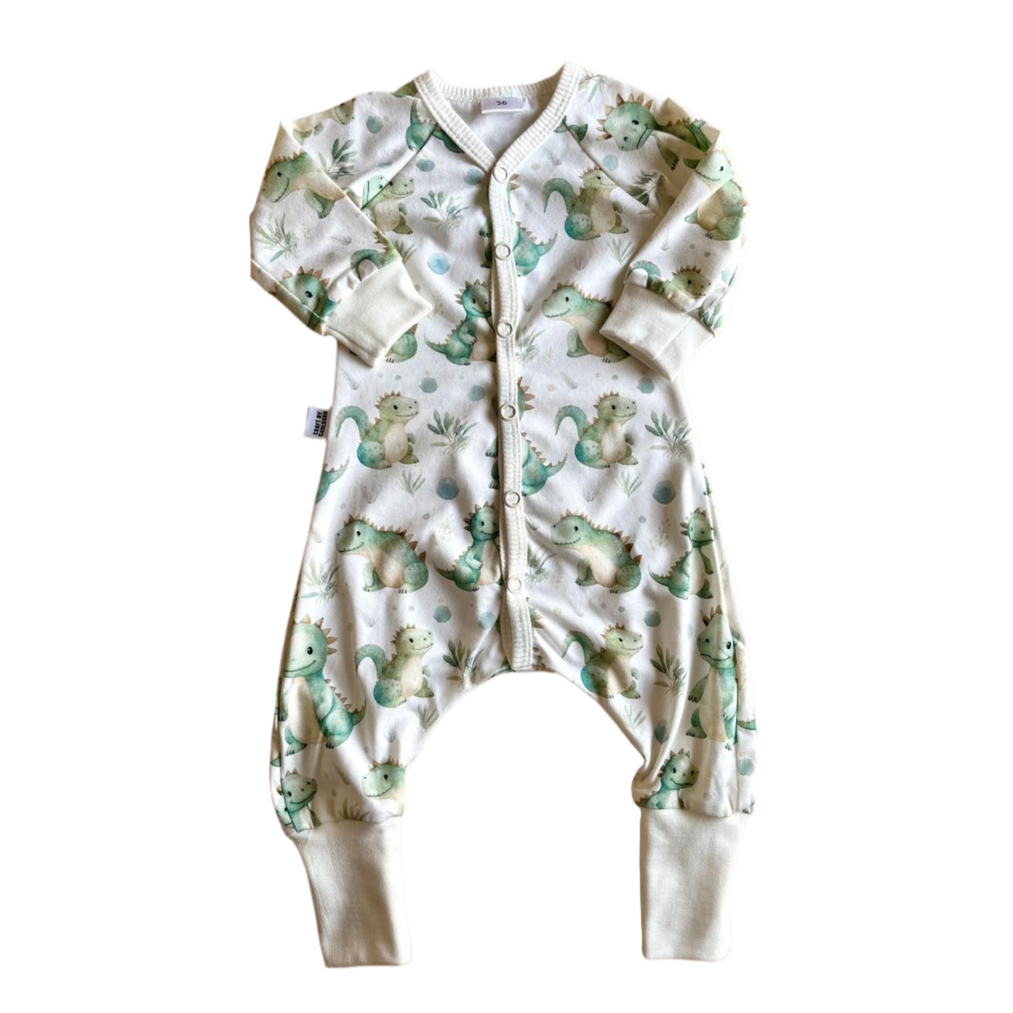 Vit barnpyjamas med långa ärmar och ben. Tyget har ett mönster av gulliga, gröna, snälla drakar.