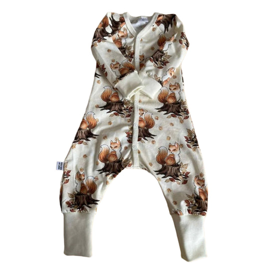 Babypyjamas med tryckknappar och långa ärmar och ben. Vit botten med mönster av söta bruna rävar. 