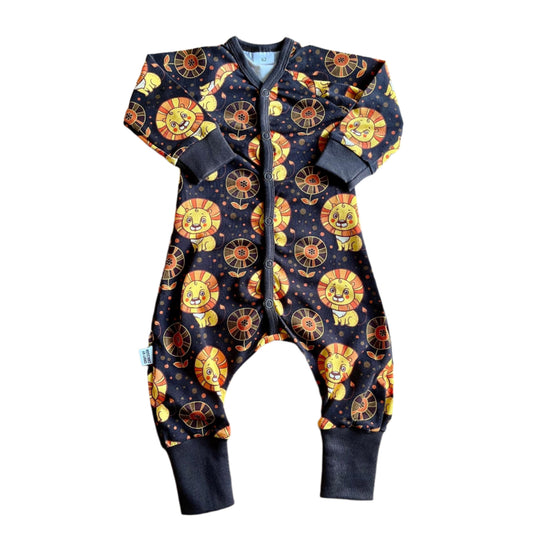 Svart barnpyjamas med långa ärmar och ben. Gulligt mönster med stora snälla lejon i gult och orange. 